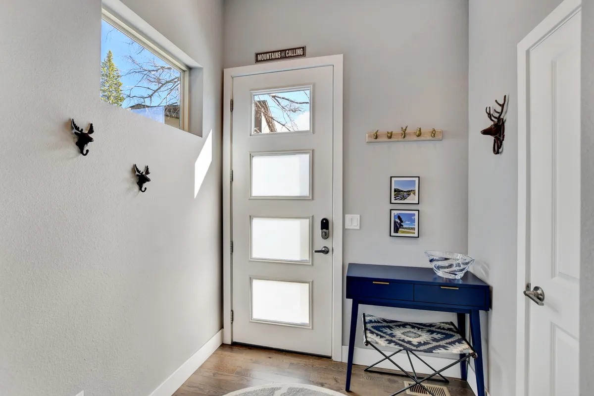 This image captures the front door area with a blue console table, wall art, and hooks on the wall—an inviting entrance space where guests would start and end their daily adventures. The natural light and welcoming decor evoke a sense of coming and going, which fits the digital nomad lifestyle of blending work with exploration.