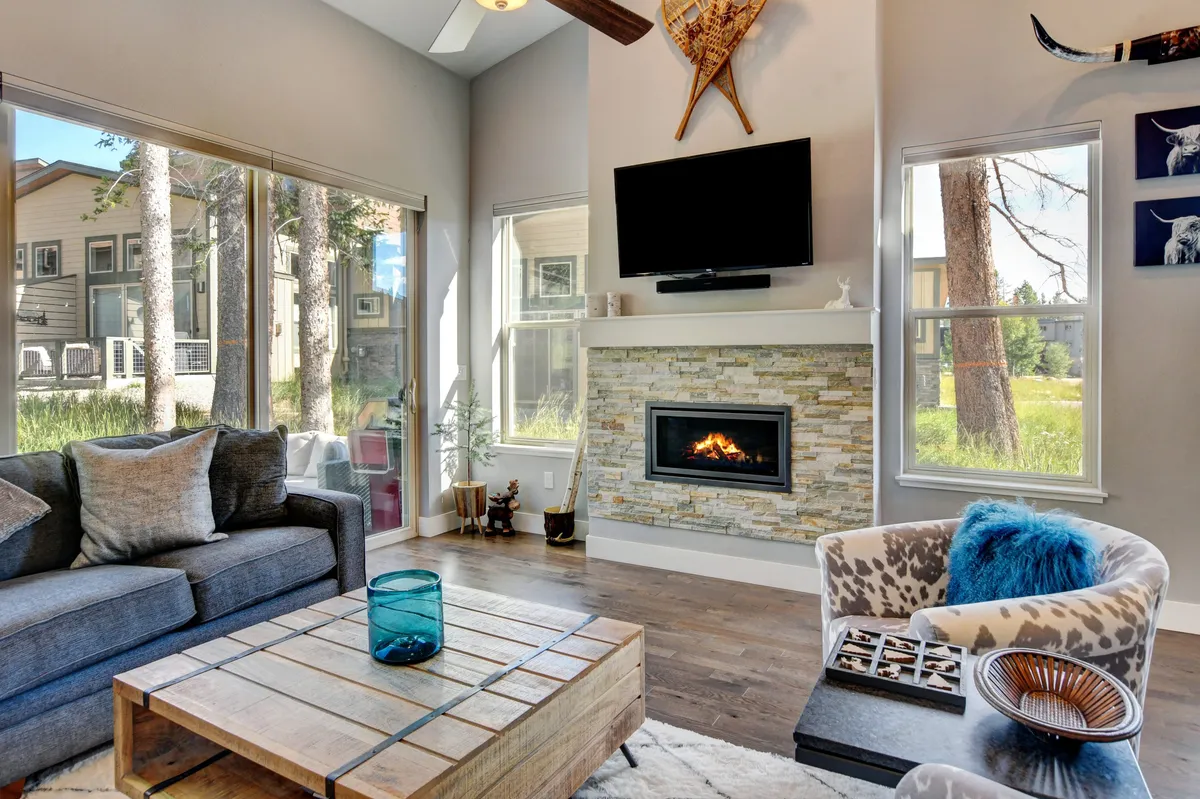 A cozy living room with a modern gas fireplace as the focal point, a plush sofa and coffee table for socializing, and expansive windows that let in abundant natural light. The arrangement is perfect for relaxing, watching TV, or gathering around the fire on chilly evenings.