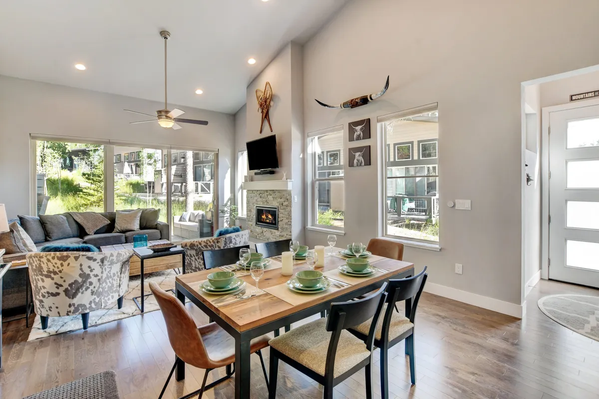 The dining area set for a meal, with a fireplace and large windows overlooking the outdoors. The décor is warm and inviting, perfect for gatherings, meals, and game nights with friends and family.